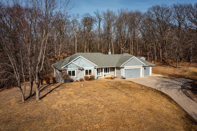 view of front of property featuring a front lawn, concrete driveway, roof with shingles, a chimney, and a garage