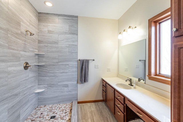 bathroom with vanity, baseboards, and tiled shower