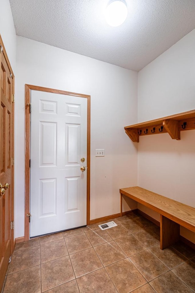 mudroom featuring tile patterned floors, visible vents, baseboards, and a textured ceiling