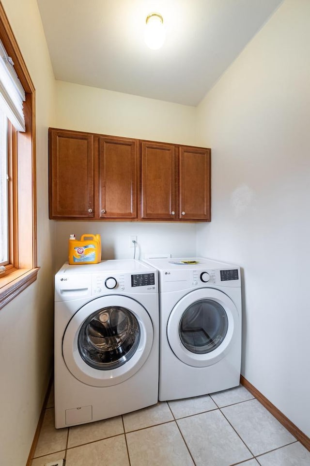 washroom with baseboards, cabinet space, light tile patterned flooring, and washer and clothes dryer