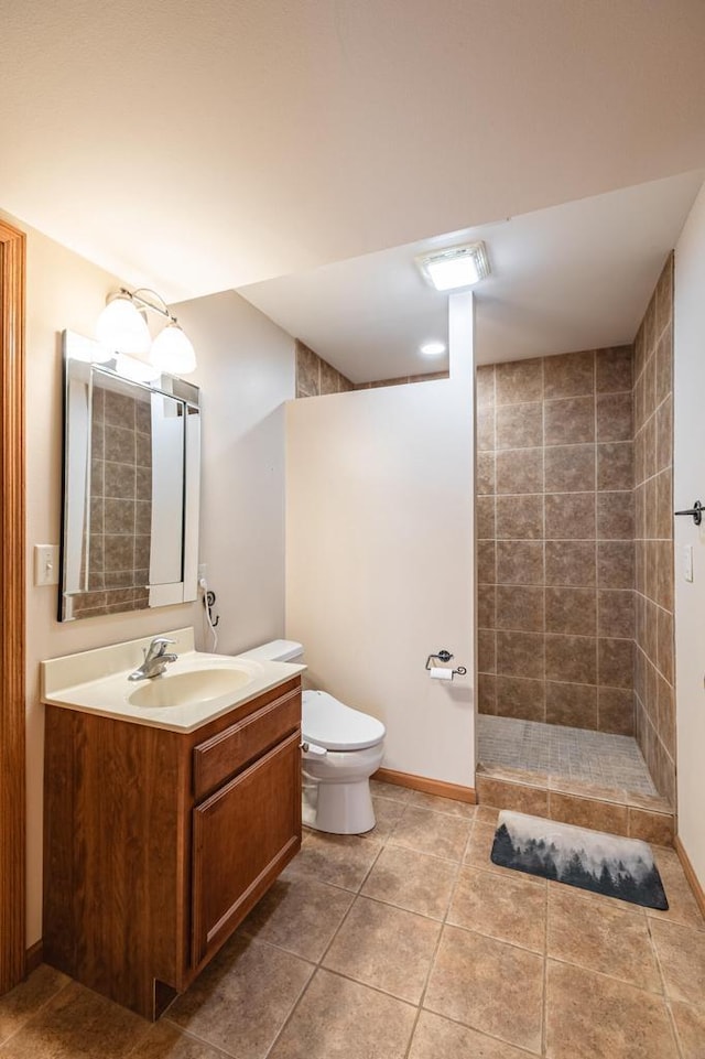 bathroom featuring vanity, baseboards, a tile shower, tile patterned flooring, and toilet