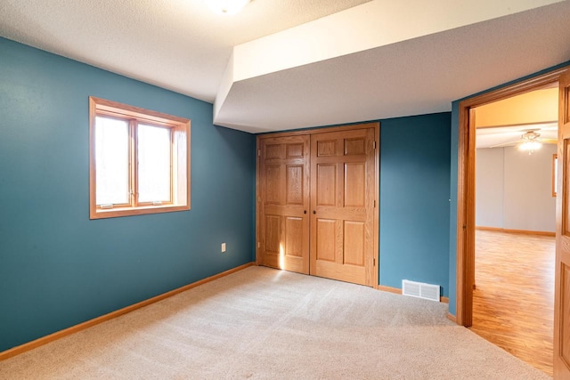 unfurnished bedroom with carpet, visible vents, baseboards, a closet, and a textured ceiling