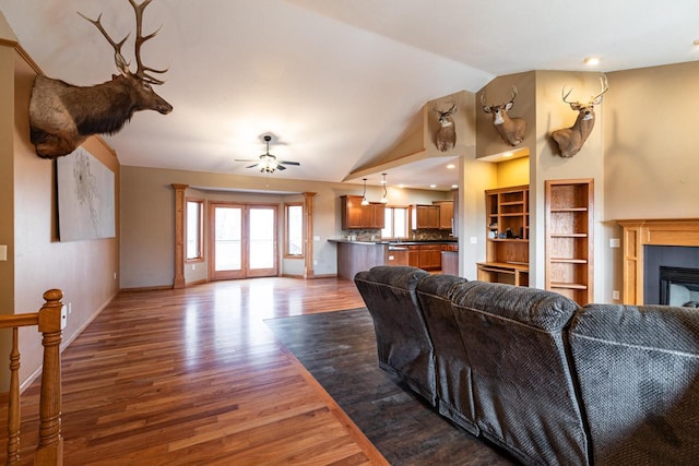 living room with vaulted ceiling, a fireplace, baseboards, and dark wood-style flooring