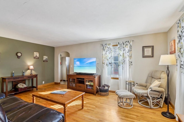 living room featuring arched walkways, baseboards, and wood finished floors