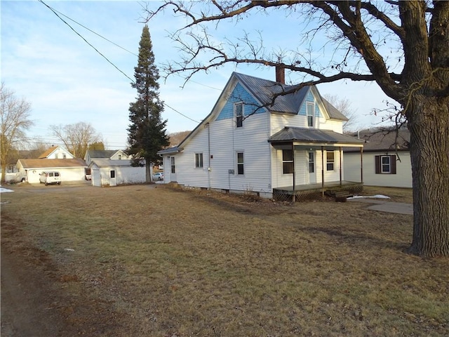 view of side of home featuring a chimney, a yard, and metal roof