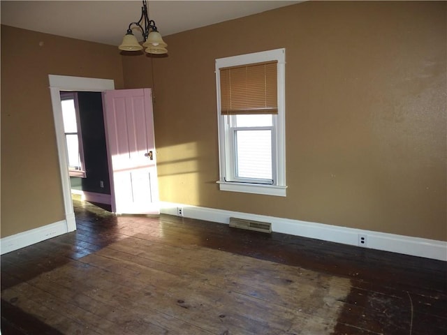 spare room featuring visible vents, an inviting chandelier, dark wood-type flooring, and baseboards