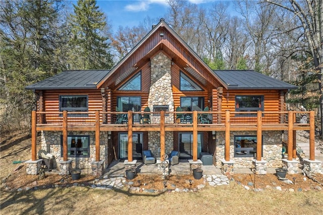 rear view of house featuring stone siding, a patio, and log exterior