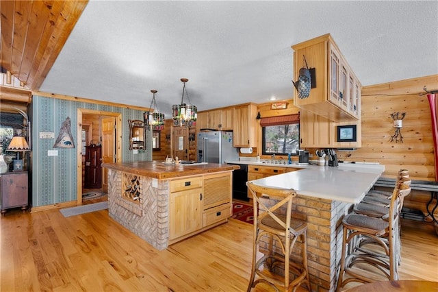 kitchen with high quality fridge, light wood-style flooring, light brown cabinetry, and black dishwasher