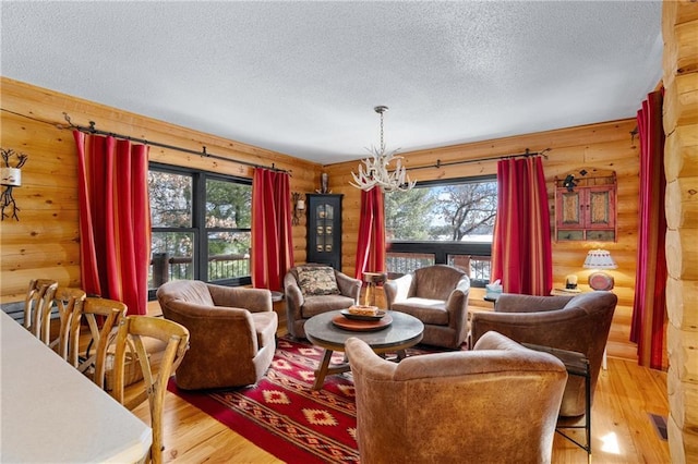 living area with a chandelier, a textured ceiling, a healthy amount of sunlight, and light wood-style flooring