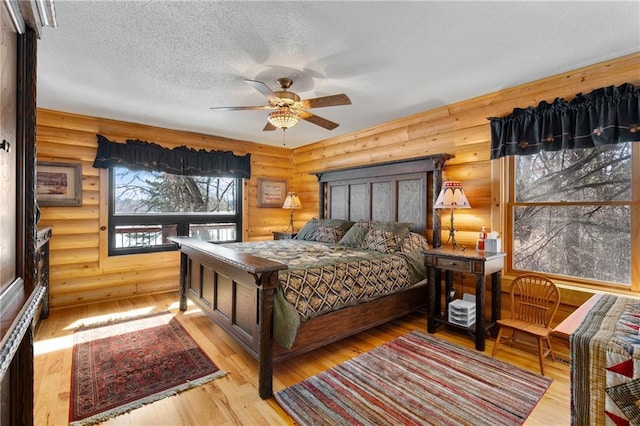 bedroom with rustic walls, a textured ceiling, and wood-type flooring