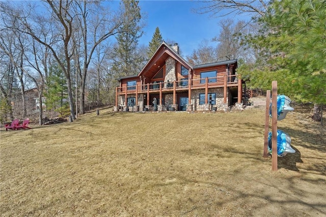 back of property featuring log exterior, a lawn, stone siding, and a chimney