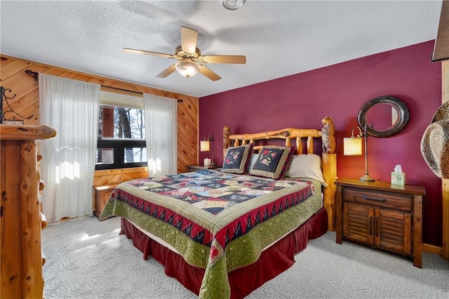 carpeted bedroom featuring ceiling fan, a textured ceiling, and wood walls