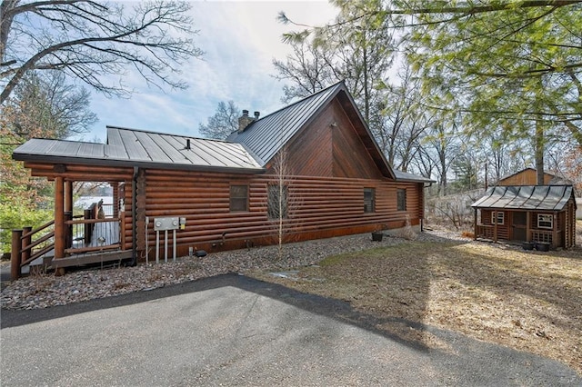 view of side of property with a chimney, log exterior, metal roof, and a standing seam roof