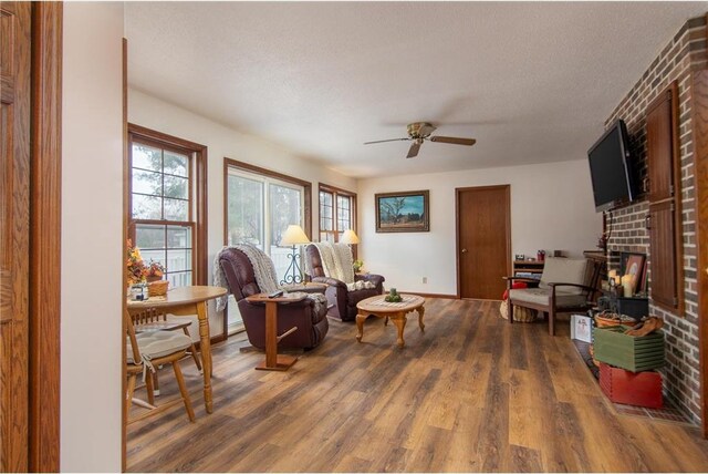 227 Donatelle St, Amery, WI 54001 - living area featuring ceiling fan, a textured ceiling, a brick fireplace, and wood finished floors
