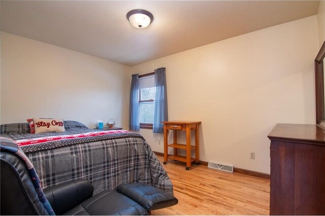 227 Donatelle St, Amery, WI 54001 - bedroom featuring visible vents, baseboards, a textured ceiling, and wood finished floors