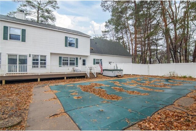 227 Donatelle St, Amery, WI 54001 - back of house featuring fence, a fenced in pool, a shingled roof, a hot tub, and a deck
