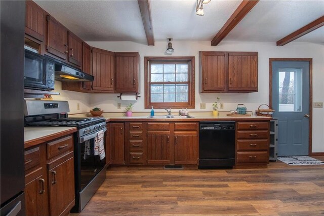 227 Donatelle St, Amery, WI 54001 - kitchen with dark wood finished floors, beam ceiling, a sink, black appliances, and under cabinet range hood