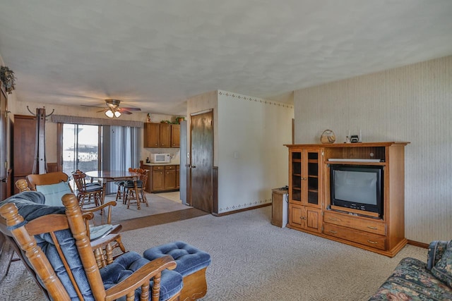 living area featuring baseboards, light colored carpet, and a ceiling fan