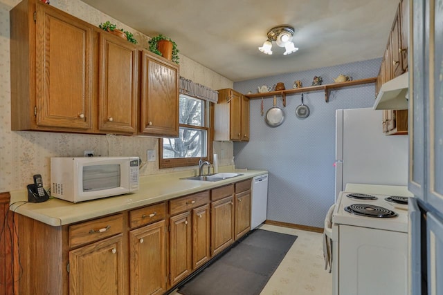 kitchen with under cabinet range hood, a sink, white appliances, wallpapered walls, and light floors