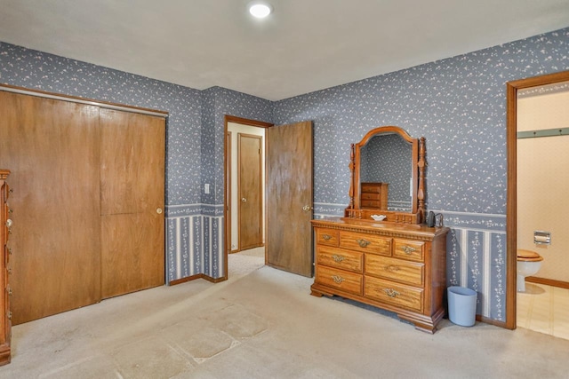 carpeted bedroom with a closet, ensuite bathroom, and wallpapered walls