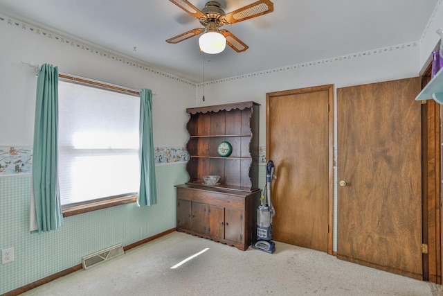 unfurnished bedroom featuring visible vents, wallpapered walls, ceiling fan, carpet floors, and wainscoting