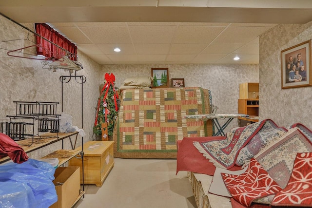 living area with recessed lighting, a drop ceiling, concrete flooring, and wallpapered walls