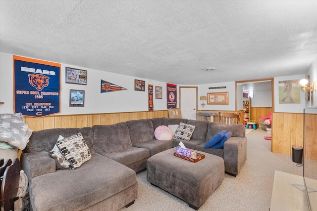 carpeted living area with a wainscoted wall, a textured ceiling, and wood walls