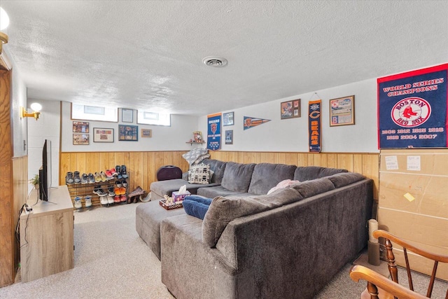 living room with a textured ceiling, visible vents, carpet floors, and wainscoting