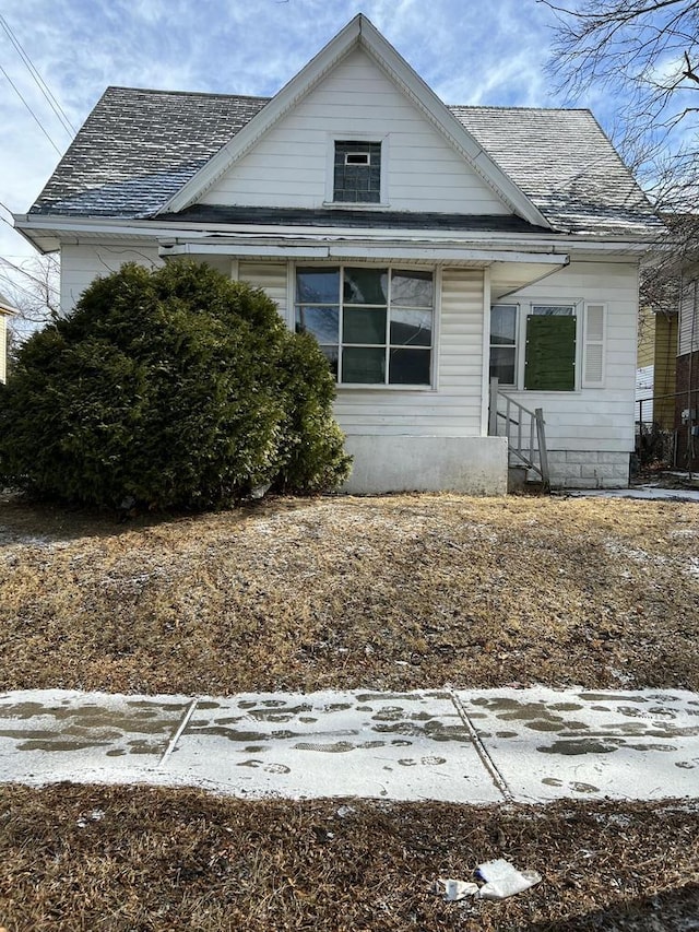 bungalow-style home with roof with shingles