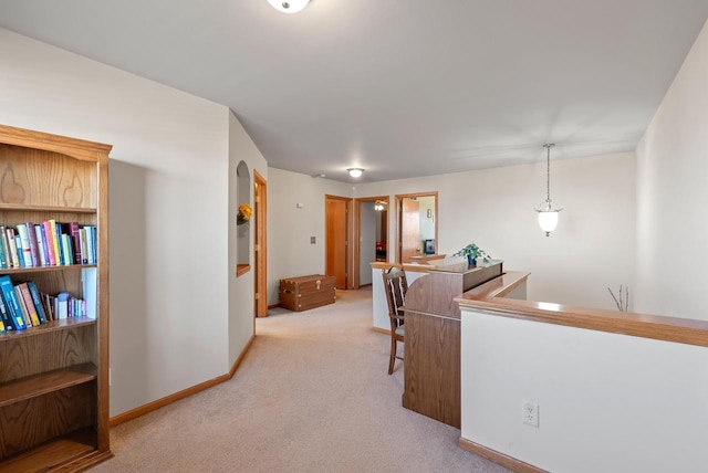 hallway featuring light colored carpet and baseboards