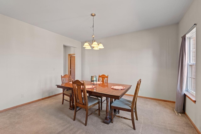 dining space with light colored carpet, baseboards, and an inviting chandelier