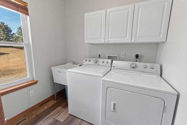 laundry area with wood finished floors, baseboards, visible vents, washing machine and clothes dryer, and cabinet space