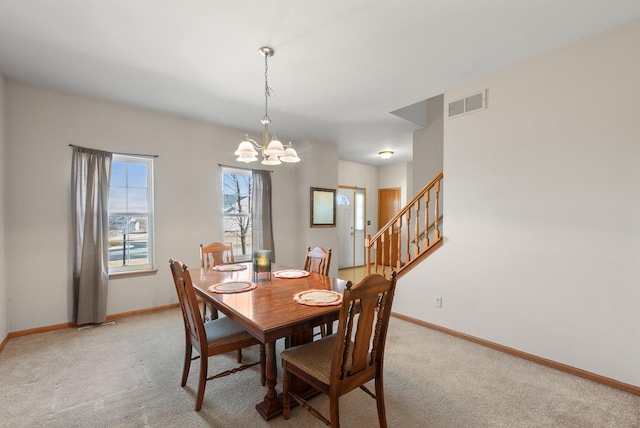 dining room with an inviting chandelier, baseboards, visible vents, and light carpet