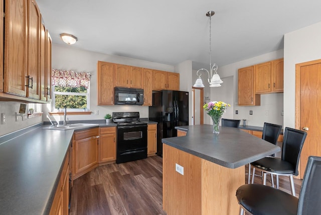 kitchen featuring black appliances, a breakfast bar, a sink, a kitchen island, and dark wood finished floors