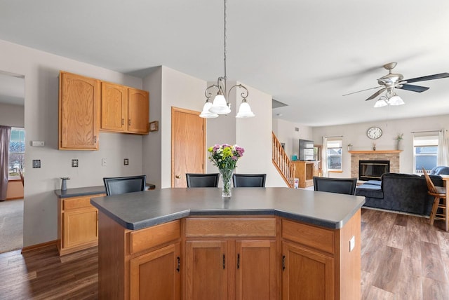 kitchen with a glass covered fireplace, pendant lighting, dark wood-style floors, and a center island