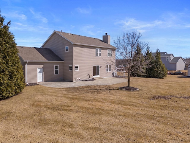 rear view of property with a lawn, a chimney, and a patio area