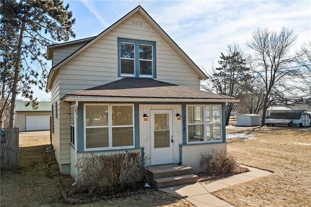 view of front of home featuring roof with shingles, an outdoor structure, and entry steps