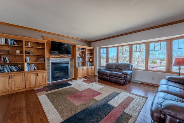 living area featuring visible vents, crown molding, baseboards, dark wood-type flooring, and a fireplace