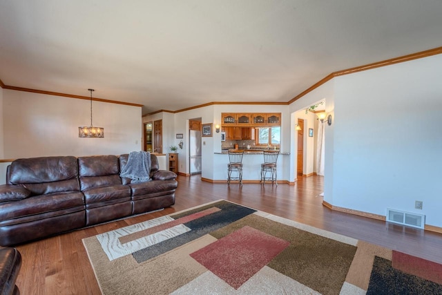 living area featuring baseboards, wood finished floors, visible vents, and a chandelier