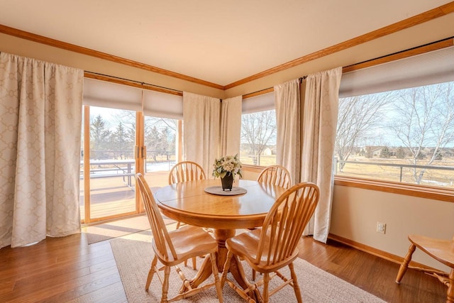 dining space featuring crown molding, baseboards, and wood finished floors