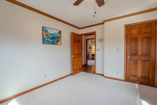 unfurnished bedroom featuring a ceiling fan, crown molding, baseboards, and carpet floors