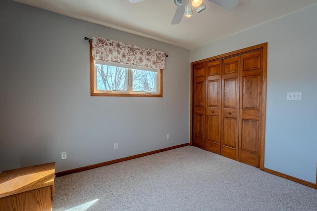 unfurnished bedroom with carpet flooring, baseboards, a closet, and ceiling fan