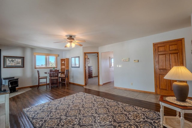 living room with a wood stove, baseboards, and wood finished floors