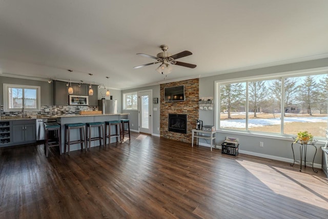 living room featuring baseboards, a fireplace, dark wood-style flooring, and crown molding