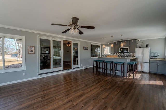 kitchen with gray cabinets, appliances with stainless steel finishes, a breakfast bar area, and ornamental molding