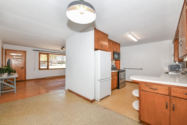 kitchen featuring light floors, stainless steel electric stove, freestanding refrigerator, a sink, and black microwave