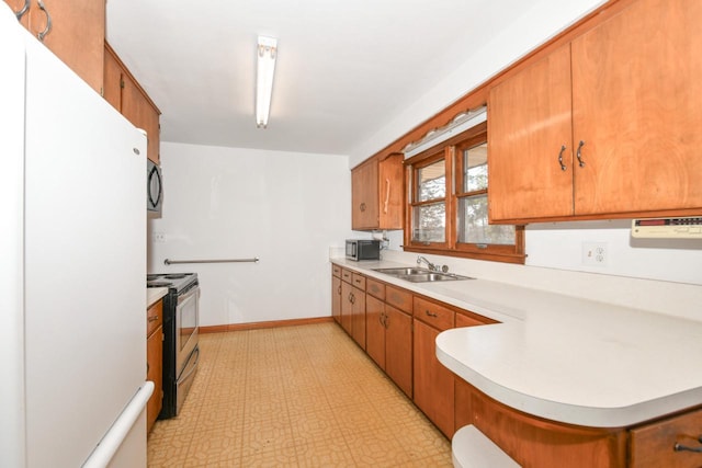 kitchen with light floors, a sink, light countertops, appliances with stainless steel finishes, and brown cabinets