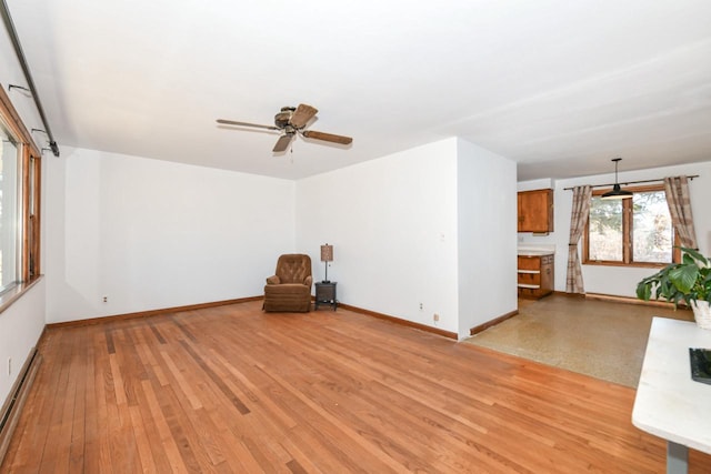 unfurnished room featuring a baseboard heating unit, baseboards, and light wood-style flooring