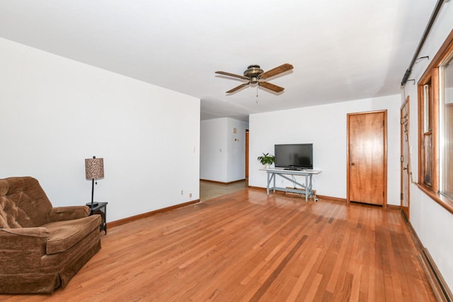 living area with a ceiling fan, baseboards, and light wood finished floors