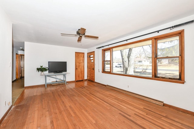 unfurnished living room featuring a baseboard heating unit, hardwood / wood-style flooring, a ceiling fan, and baseboards